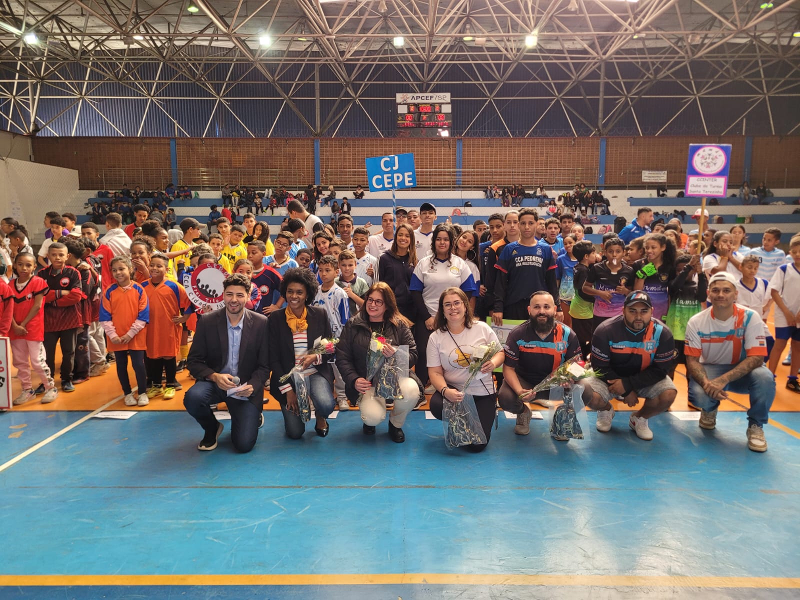 Na imagem, estão reunidos no ginásio esportivo os organizadores do evento, além das crianças e adolescentes em fil